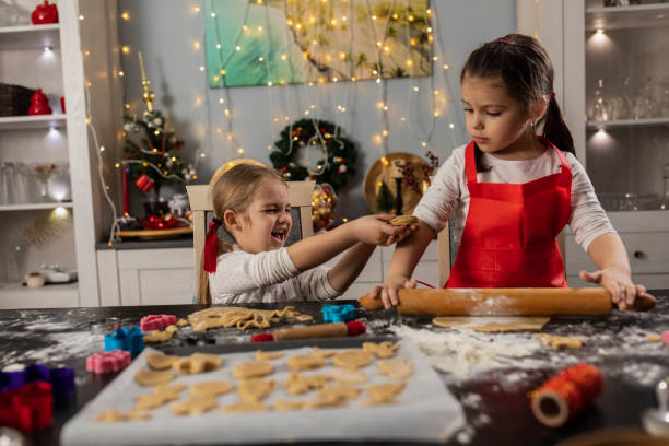 istock Two cute little girls working as a team on making gingerbread cookies 1320187615