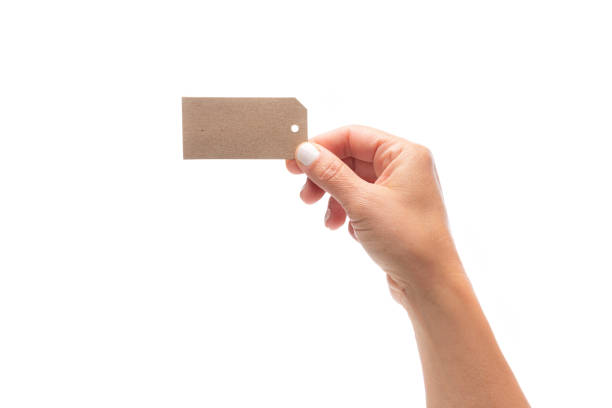 istock Fingers holding blank brown tag isolated on white 1320187943