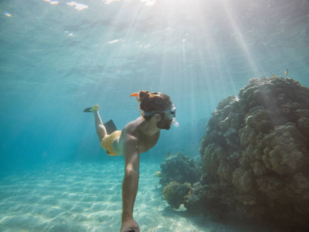 istock Man takes selfie underwater, clear blue sea 1320189037