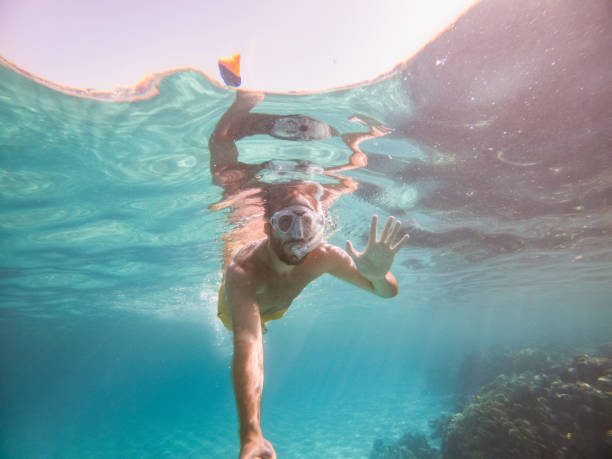 istock Man takes selfie underwater, clear blue sea 1320189038