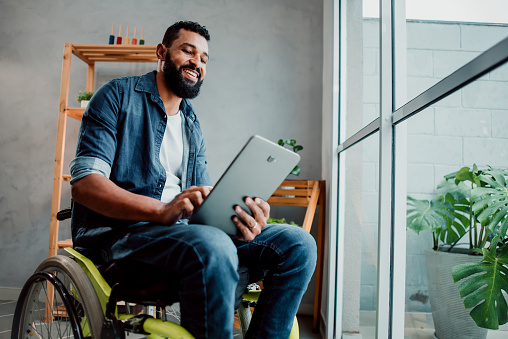 Man in a wheelchair using digital tablet