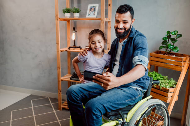 istock Father in wheelchair doing selfie on smartphone with daughter 1320193461