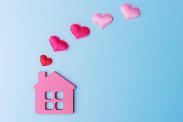 istock Pink toy house and decorative hearts on light blue background with copy space 1320198982