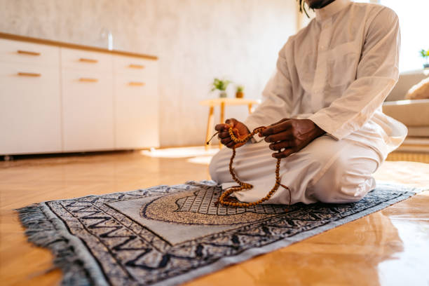 Muslim man holding prayer beads while praying