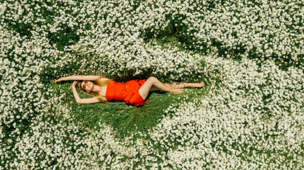 istock Beautiful woman lying on flower field 1320202580