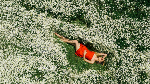 istock Beautiful woman lying on flower field 1320202847