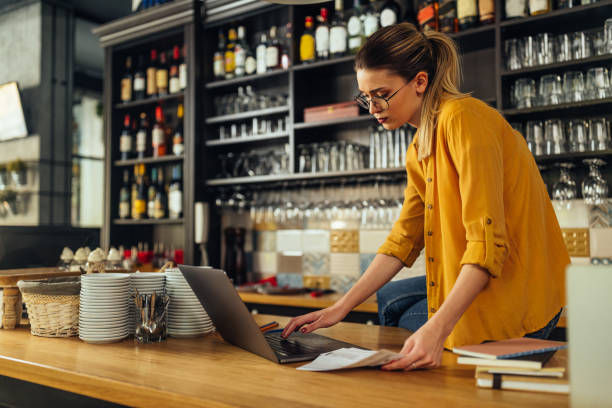istock Cafe owner working on laptop and checking bills and accounts 1320207050