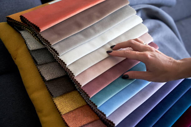 istock Choosing upholstery fabric color and texture from various colorful samples in a store. Female customer hands touching textile. 1320207213