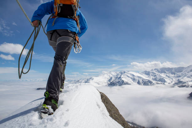 istock Mountaineer climbs out onto snowy summit with rope 1320207235