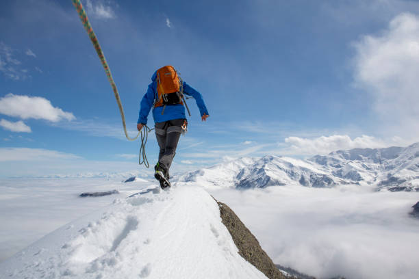 istock Mountaineer climbs out onto snowy summit with rope 1320207929