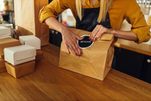 nahaufnahme der frau verpackung lebensmittel für die lieferung - lunch take out food bag paper bag stock-fotos und bilder