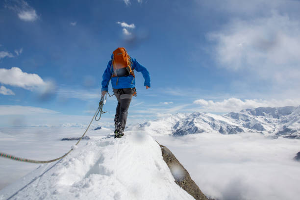 istock Mountaineer climbs out onto snowy summit with rope 1320208294