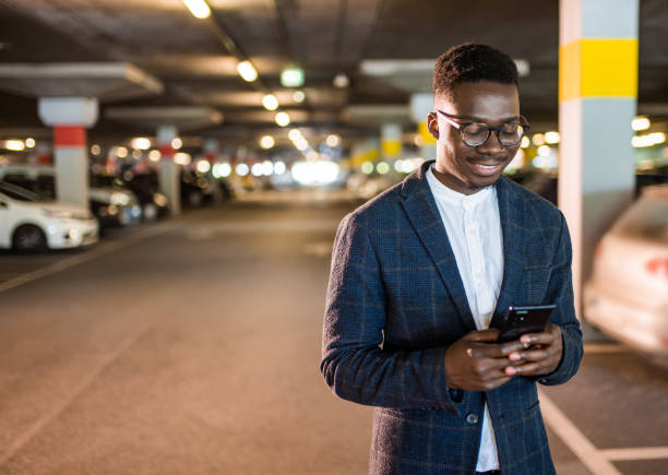istock Happy businessman texting on phone at public car garage. 1320211012