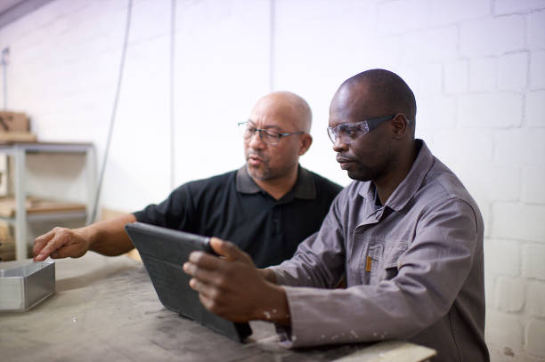 istock Side view Manufacturing Colleagues discussing designs using a digital tablet at metal bending machine 1320211318