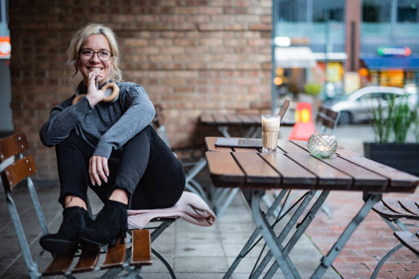 jeune femme s’asseyant dans le bar de café à l’extérieur - headphones relaxation outdoors caucasian photos et images de collection