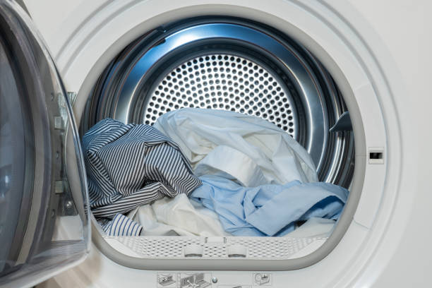 洗濯され乾燥したシャツが入っていて、ドアが開いている衣類乾燥機の目を閉じます。 - 衣類乾燥機 ストックフォトと画像