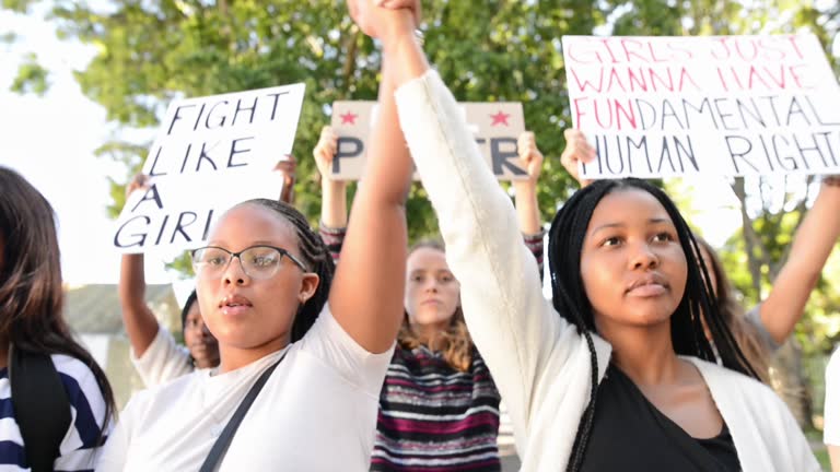 Group of diverse teenage girls holding hands during a women's march