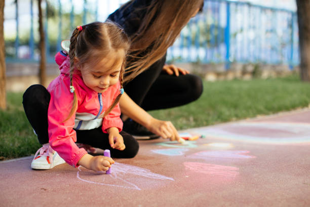 istock Little Girl Drawing with Sidewalk Chalk 1320226683