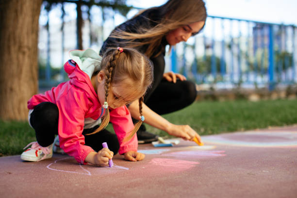 istock Little Girl Drawing with Sidewalk Chalk 1320226715