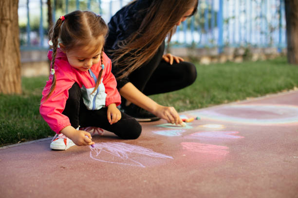 istock Little Girl Drawing with Sidewalk Chalk 1320227291