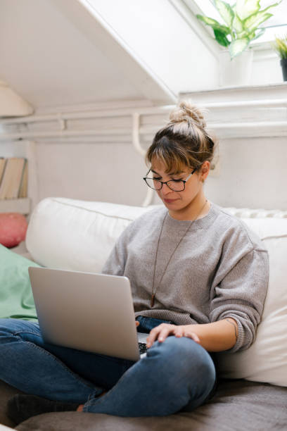 istock Young woman sitting and using laptop at home 1320227333