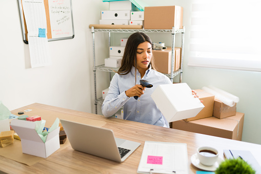 Women, owner of small business. Receiving orders and  packing products in boxes, preparing it for delivery.