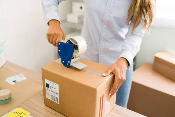 istock Young woman sealing a shipping package 1320227543
