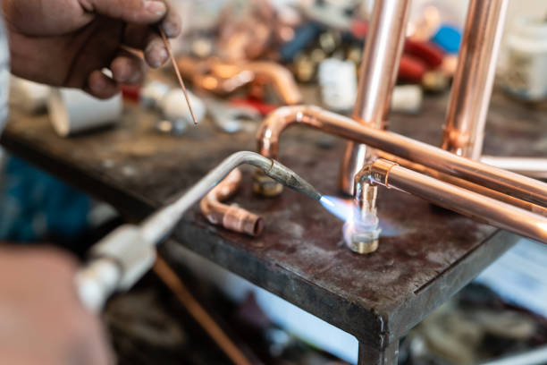 istock Close up on hands of unknown industrial worker plumber with central heating copper pipes welding using gas torch or blowtorch at work 1320228628