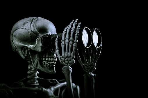 Studio shot of a skeleton Looking trough a binocular, Halloween