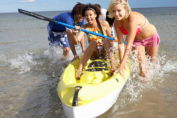 Group of teenagers playing in sea with canoe