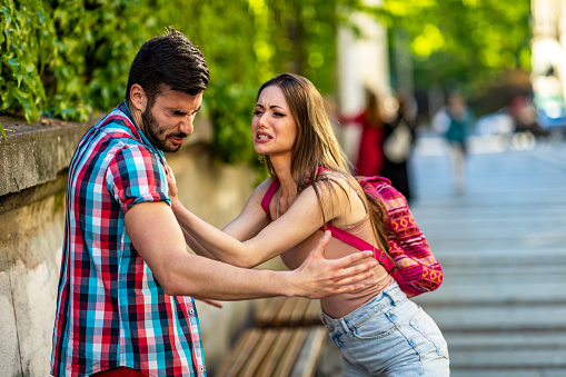 Angry man and woman quarreling on street.