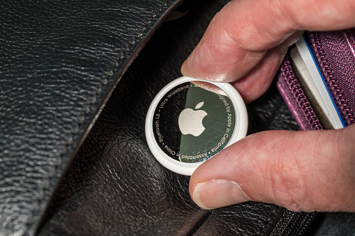 Morgantown, WV - 12 May 2021: Apple AirTag device inserted into a leather purse as concept for stalking or secret tracking of a person