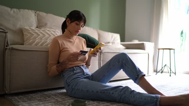 Young woman doing online shopping on smartphone at home