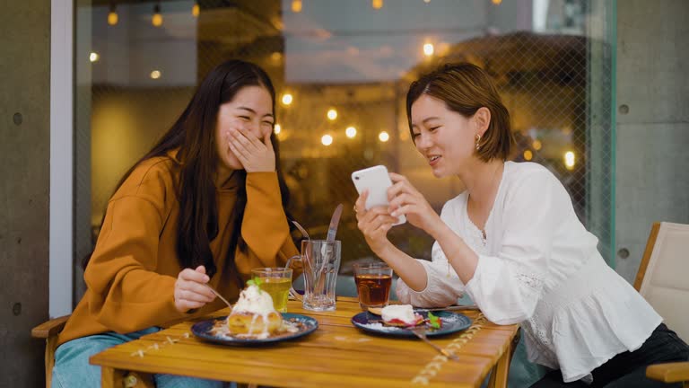 Female friends enjoying eating  sweet food in cafe and sharing their time on social media