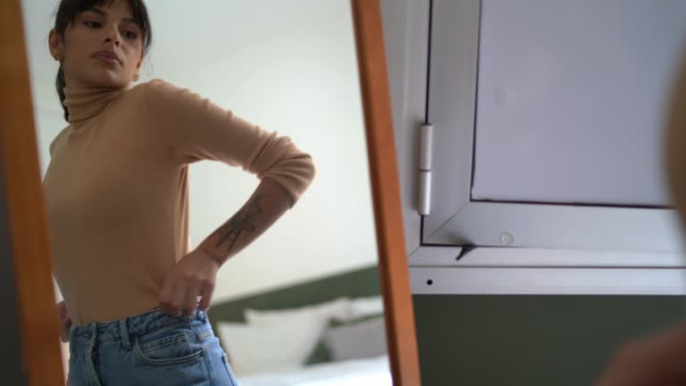 Young woman in front of a mirror trying on clothes at home