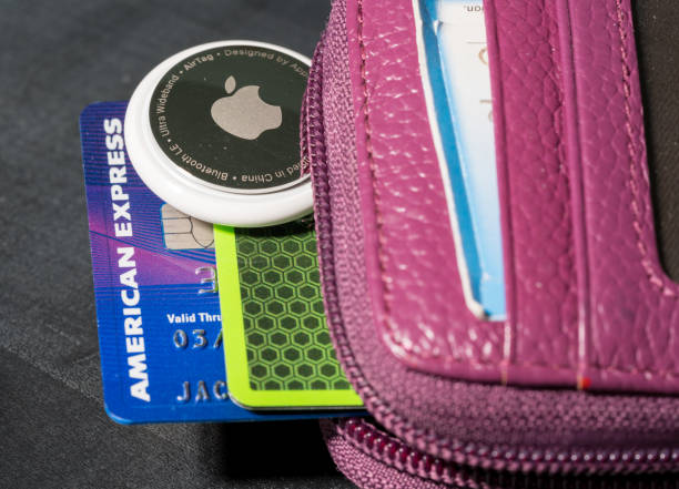 Apple AirTag being inserted in a small credit card wallet Morgantown, WV - 12 May 2021: Apple AirTag device inserted into the small credit card wallet to track its location american express stock pictures, royalty-free photos & images