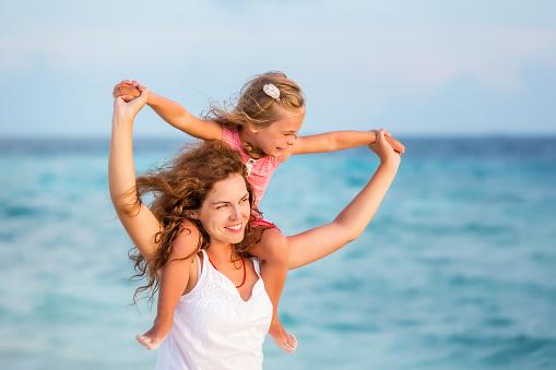 Happy mother and little daughter having fun on beach on Maldives at summer vacation. Family on the beach concept.