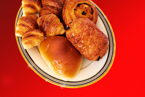 A variety of pastries on a large oval plate, red tablecloth.