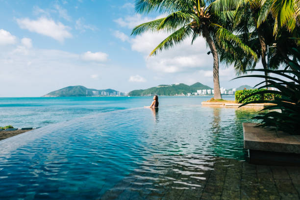 giovane donna caucasica in piscina sulla bellissima baia tropicale, cielo blu e oceano, concetto di vacanza estiva. - travel foto e immagini stock
