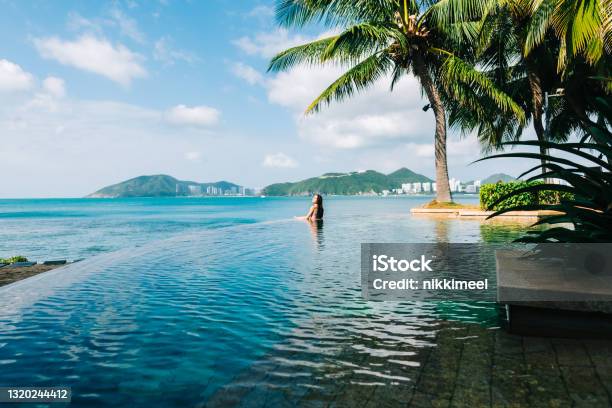 Young Caucasian Woman In Swimming Pool On Beautiful Tropical Bay Blue Sky And Ocean Summer Vacation Concept Stock Photo - Download Image Now