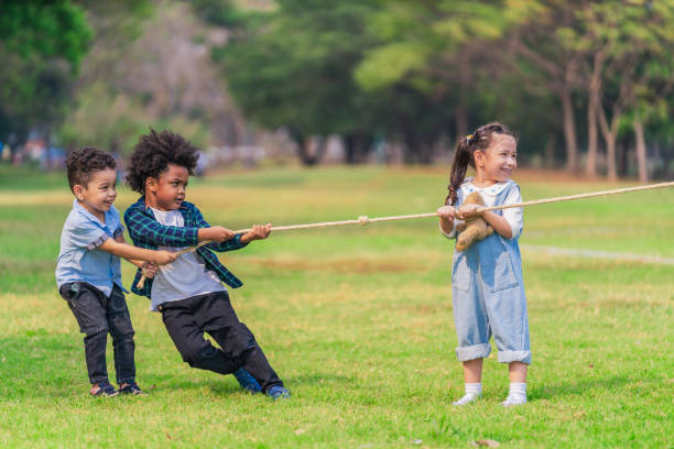 istock diverse mixed race kids boy and girl having fun playing pulling rope together in park during summer 1320249005
