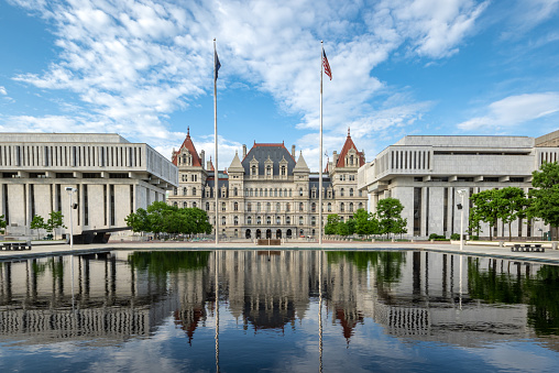 Albany, NY - USA - May 22, 2021: view of the historic New York State Capitol with reflections in the Empire State Plaza's reflecting pools