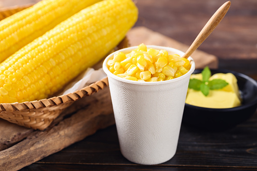 Sweetcorn with butter in a biodegradable cup on wooden background