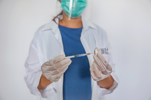 Close-up shot of Unrecognizable Asian healthcare worker extracting vaccine from vile into syringe.