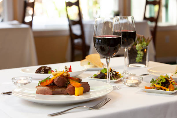 table set with food and red wine for two in restaurant - restaurant wine table table for two imagens e fotografias de stock