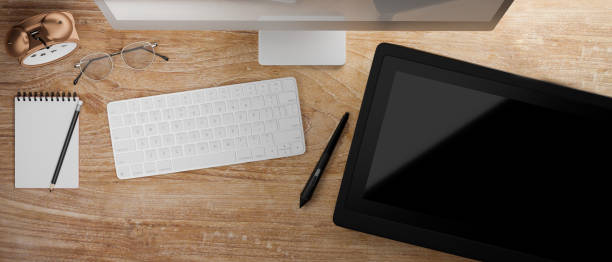 istock Top view of wooden table with computer device and drawing tablet, 3D rendering 1320263476