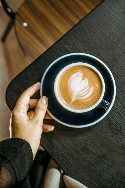 istock Cappuccino coffee cup on black wooden table lights and shadows 1320264292