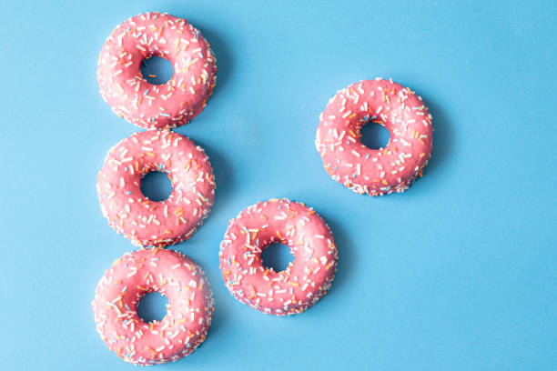 istock pink frosted donut with colorful sprinkles on blue background. copy space 1320265041
