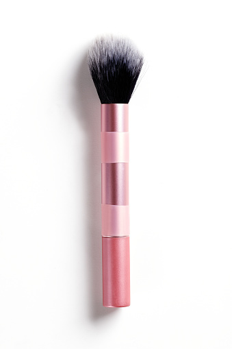 Make-up brush in pink colored container on white background with shadow