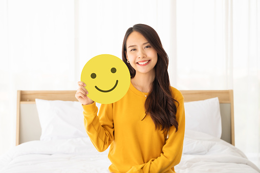 Customer service experience and business satisfaction survey. Asian woman holding paper with smiley face